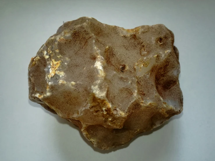 a piece of golden colored rock on a white table