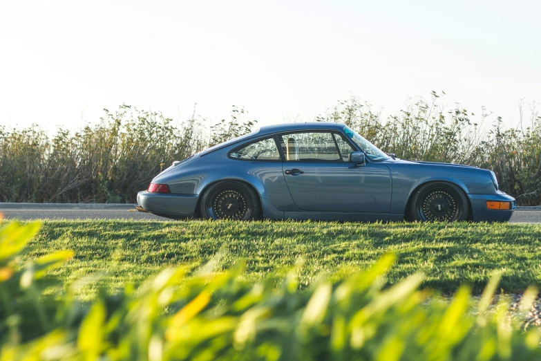 the blue porsche 9113 sits in a field by itself