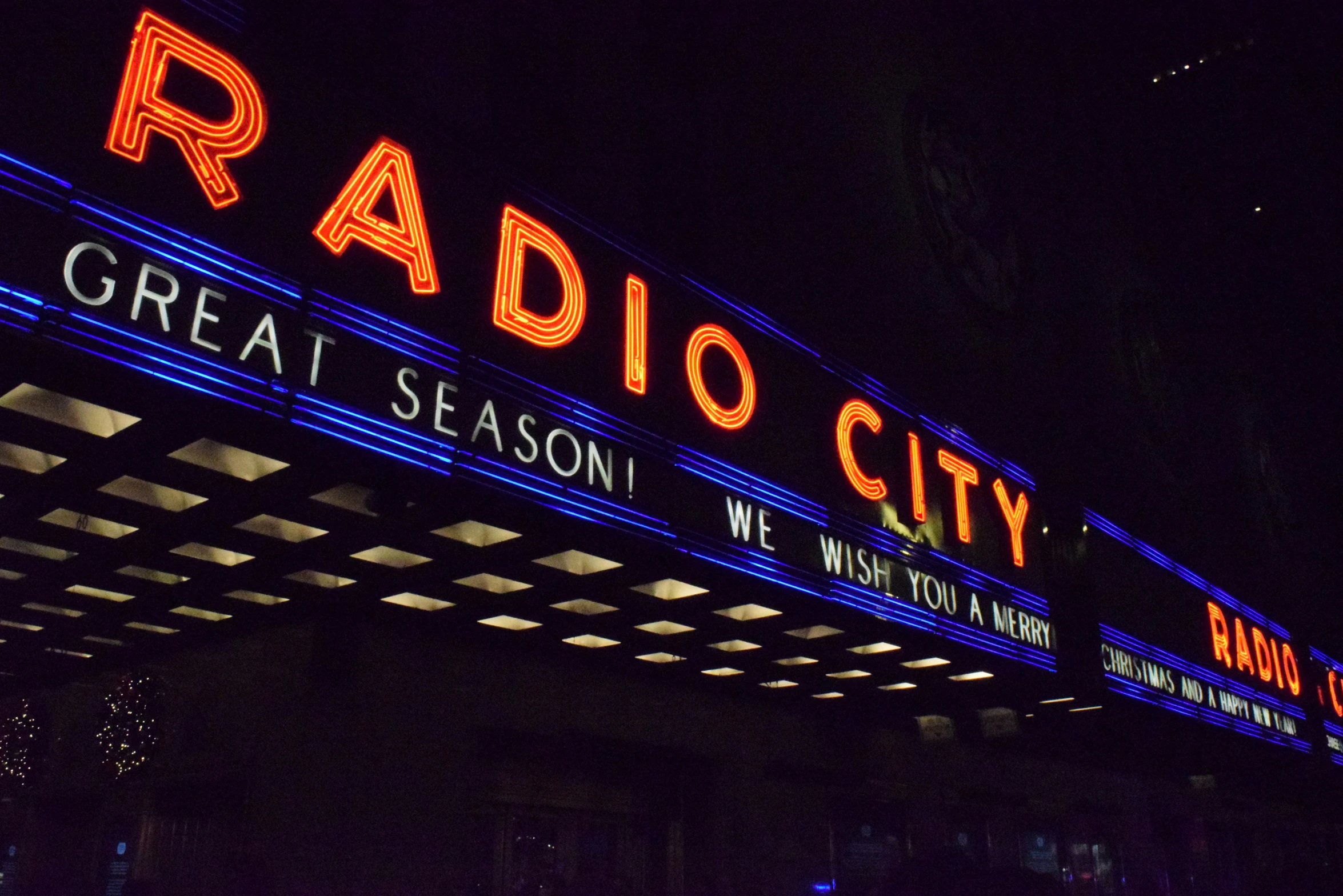 an illuminated neon sign advertising radio city in the night