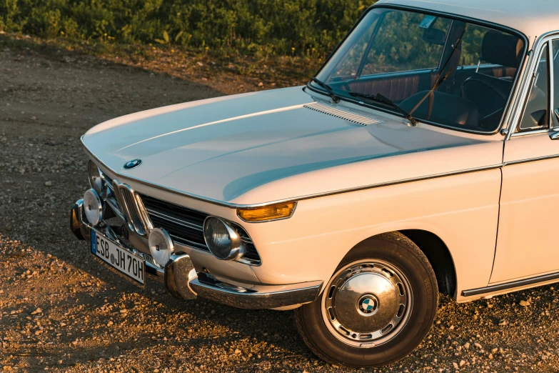 an old white and blue station wagon parked on some dirt