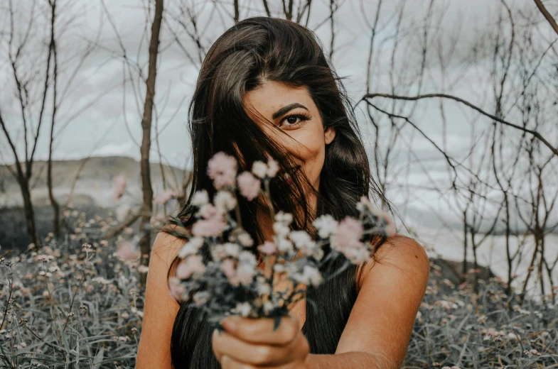 an attractive woman is holding flowers next to her face