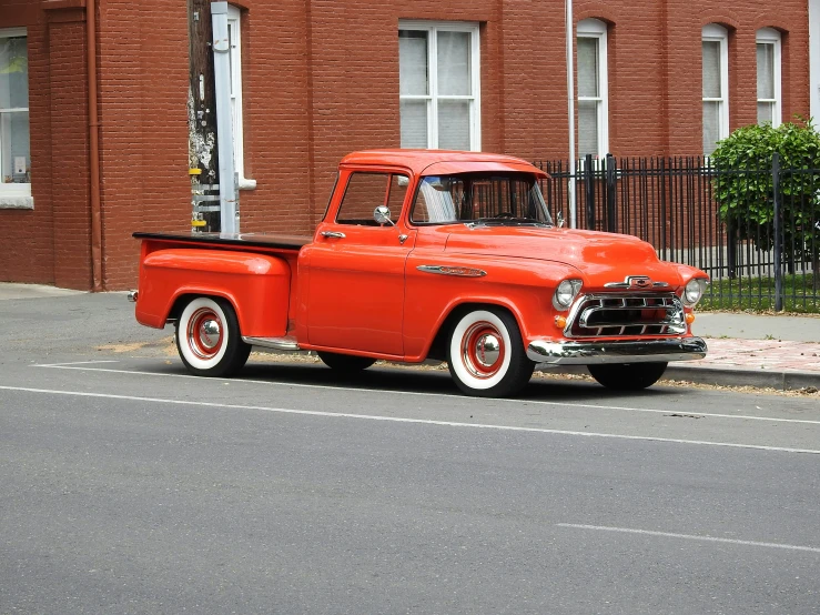 an old red pickup truck parked on the side of a street