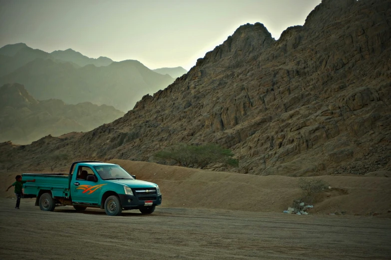 the truck is parked on the road in front of some mountains