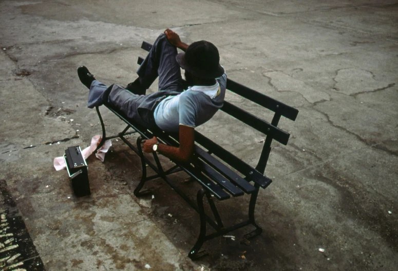 a person sitting on a bench next to a bag