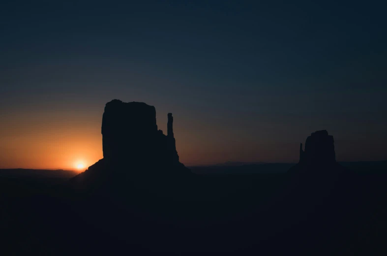 the sun setting on the horizon behind a mountain