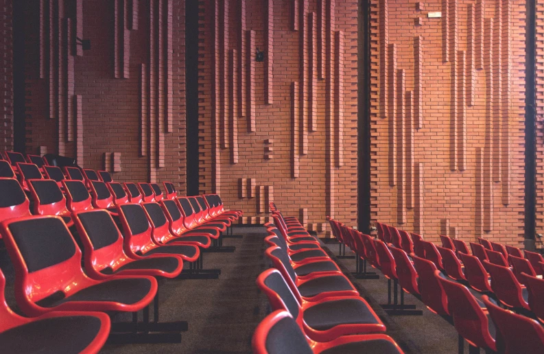 rows of red chairs in front of a brick wall