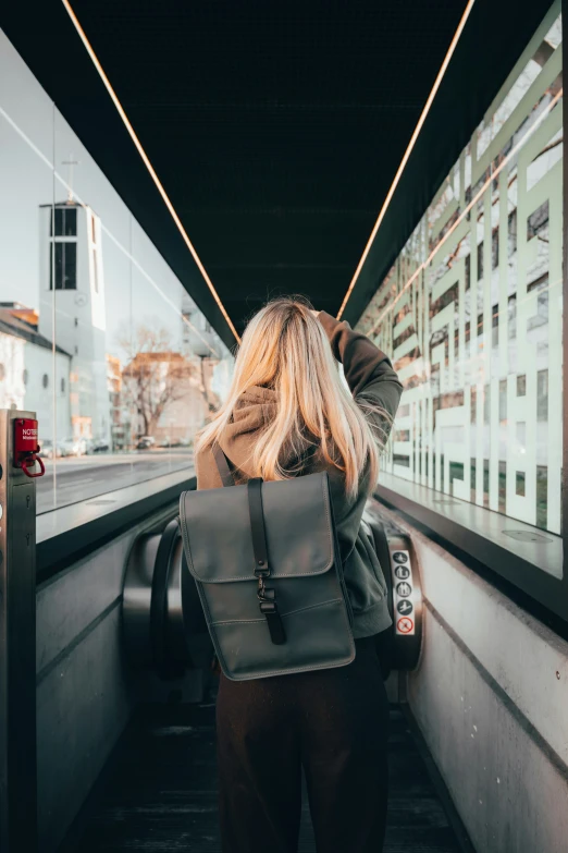 a woman with a black backpack walking down an airport walkway