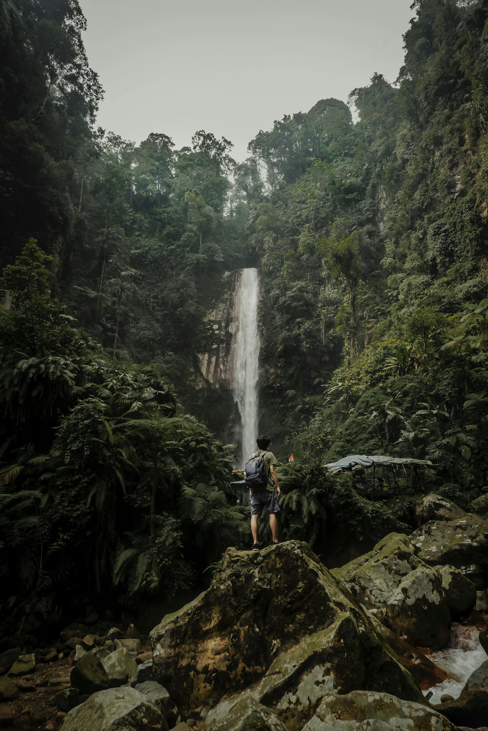 two hikers approach the bottom of a large waterfall