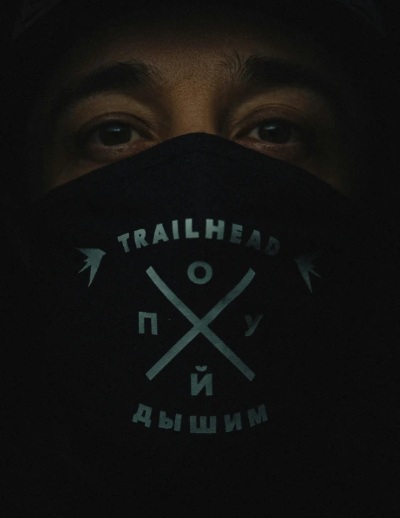 an individual with hood over his face with a patch on the forehead that says trailhead new britain