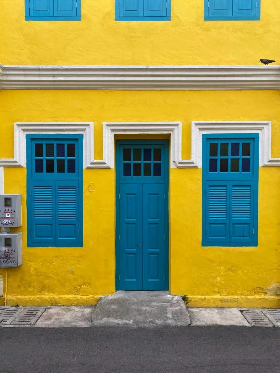 an old telephone sits outside a blue door of a yellow building