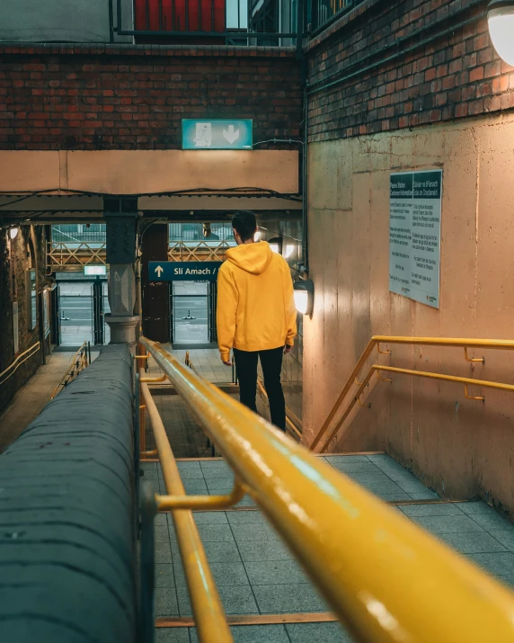 person in yellow jacket and black pants walking down a yellow stair