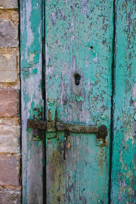 a old rusted blue door with a locked handle on an old building