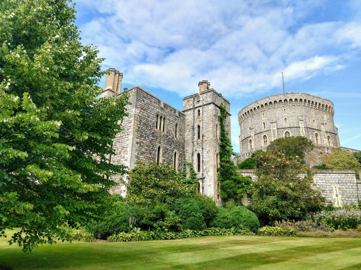 the castle with tall windows is next to trees and bushes