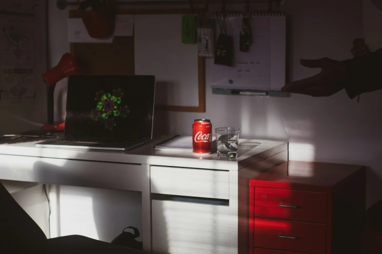 a small office area with a coke can on the desk