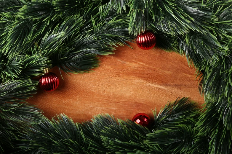 evergreen nches with red ornaments on top of a wood background