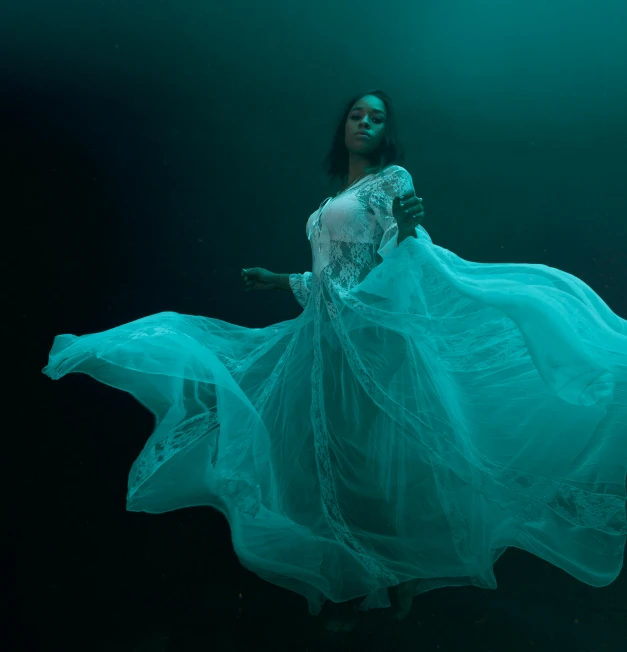 a woman standing underwater wearing a dress