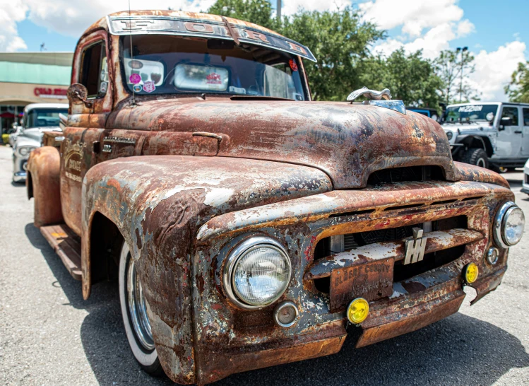 an old rusty, painted truck parked in a parking lot