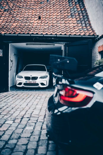 the car is in the garage next to the white bmw