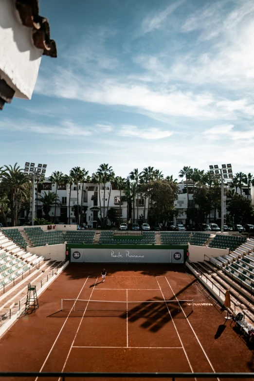 tennis court on brown clay with palm trees