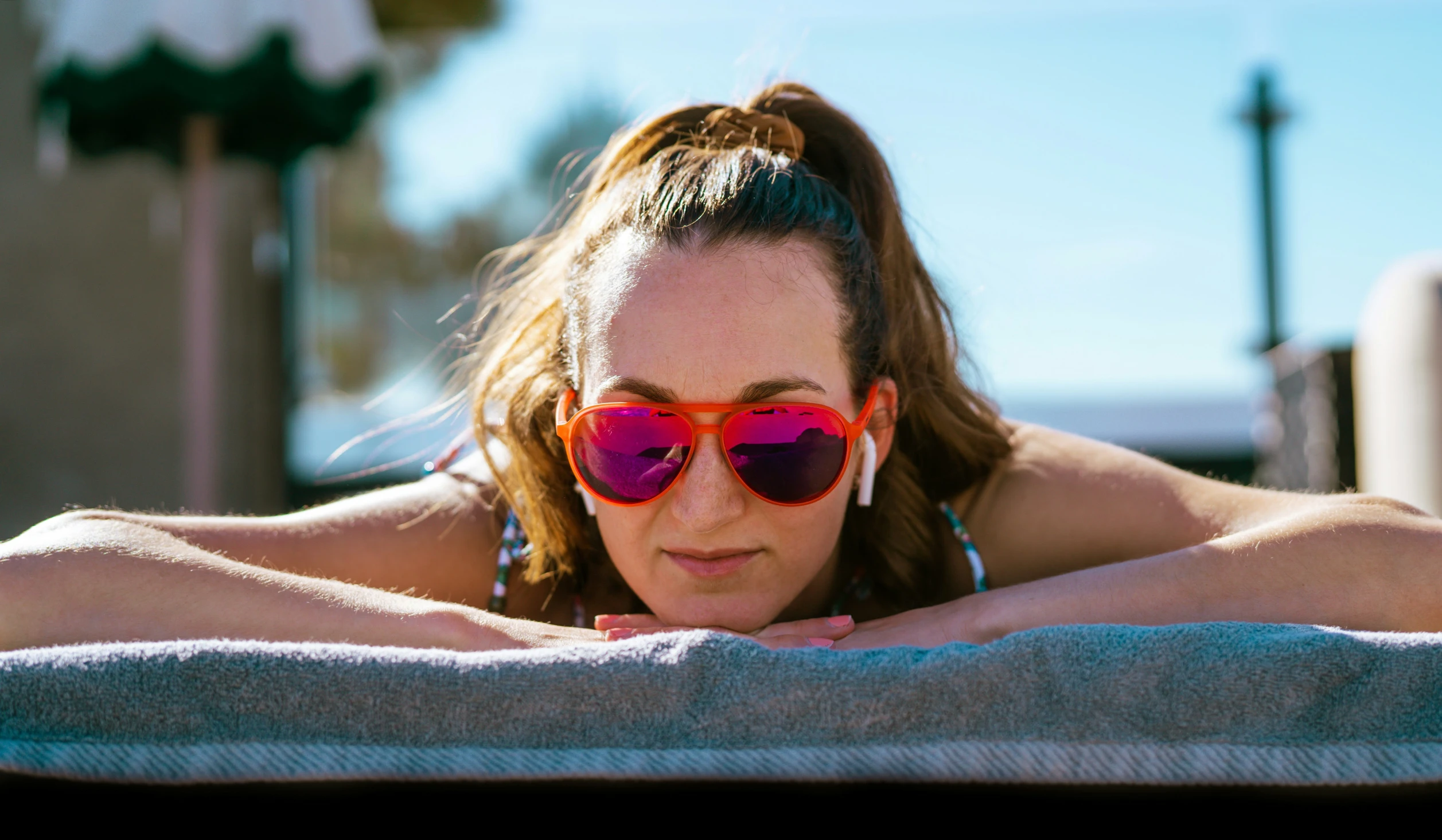 woman in sun glasses laying on a towel on the beach