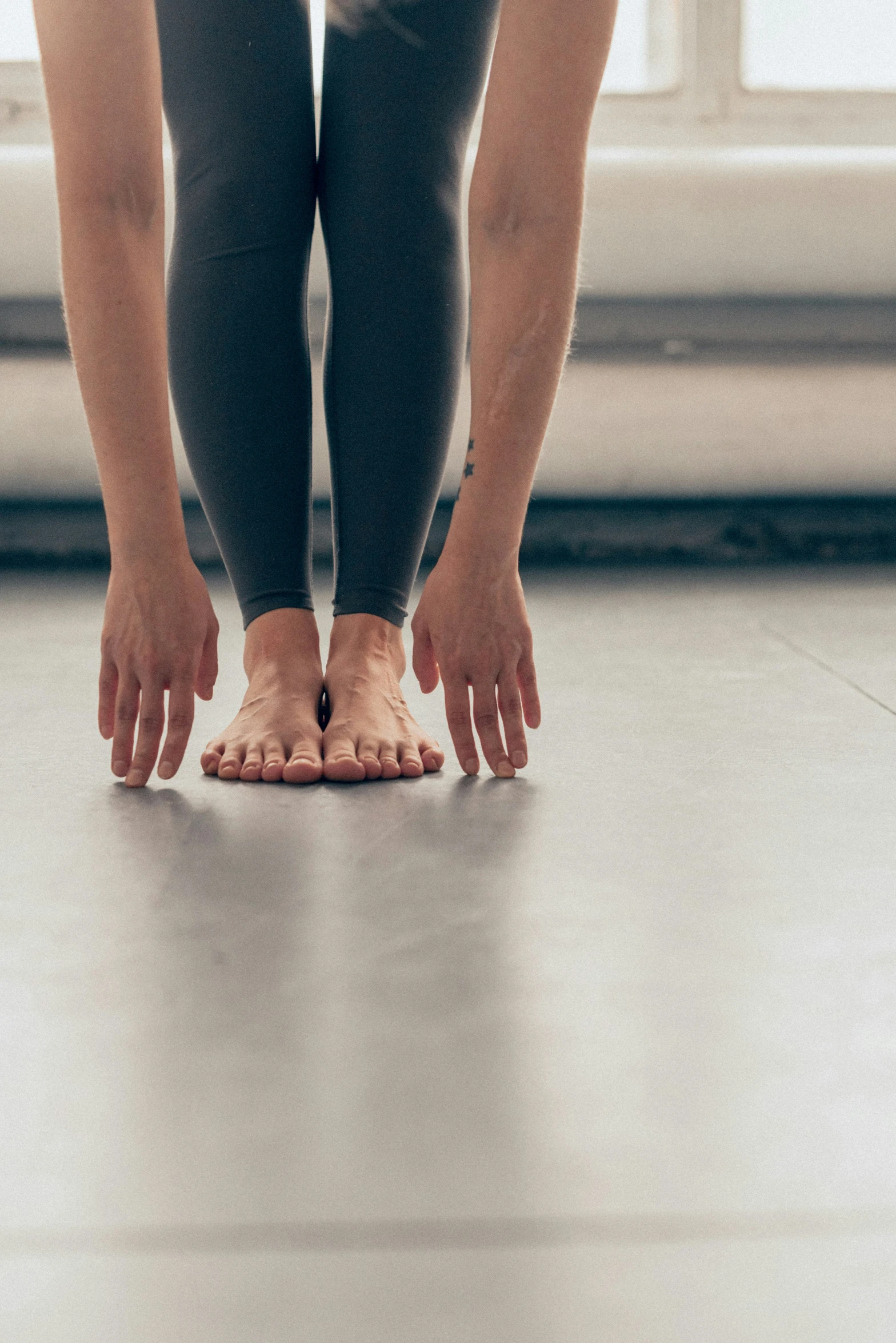 legs and feet of someone in gray leggings on a tile floor