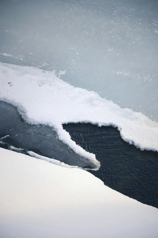 a stream of water is almost covered in snow