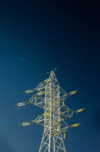 an electricity tower is shown against the dark blue sky