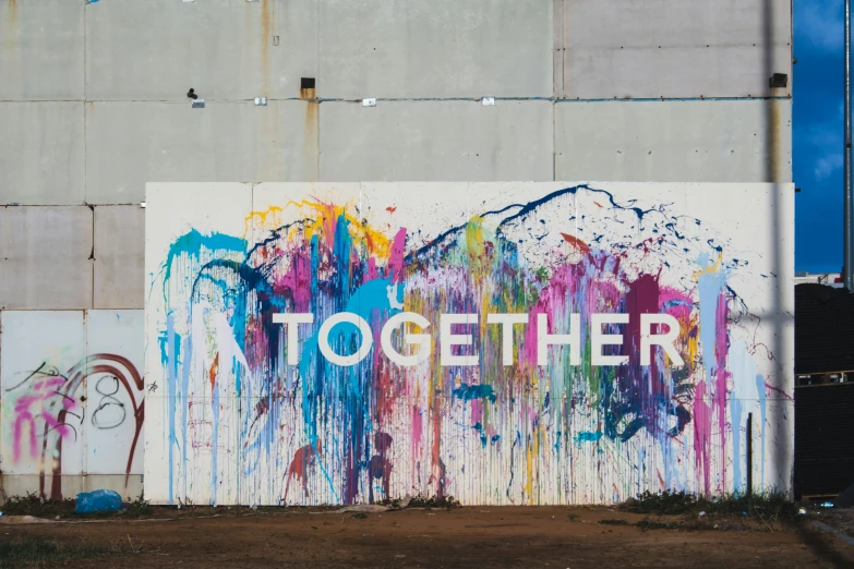 a graffiti - ridden sign on the side of a building that says, to be together
