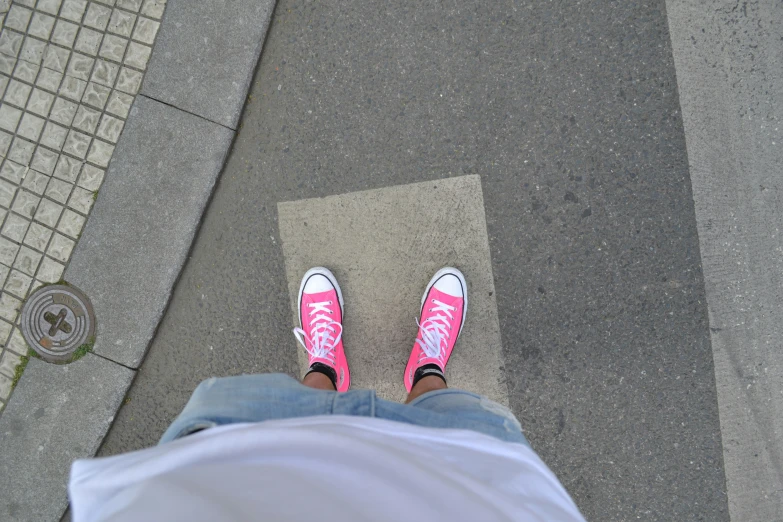 a person wearing pink sneakers and jeans standing on a street