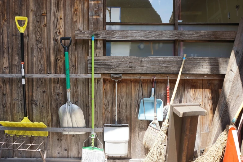 several cleaning items hanging in a wood shed