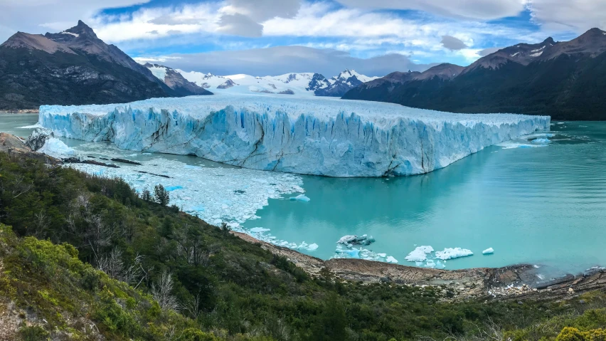 a large glacier surrounded by mountains and blue water