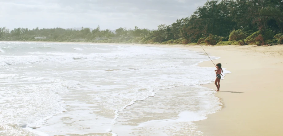 a woman is standing on a beach, and she's flying her kite