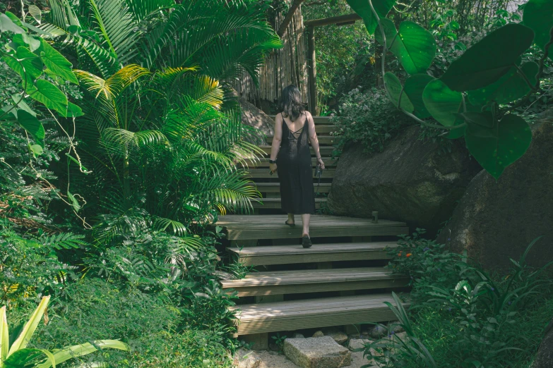 a woman wearing a black dress and walking down stairs