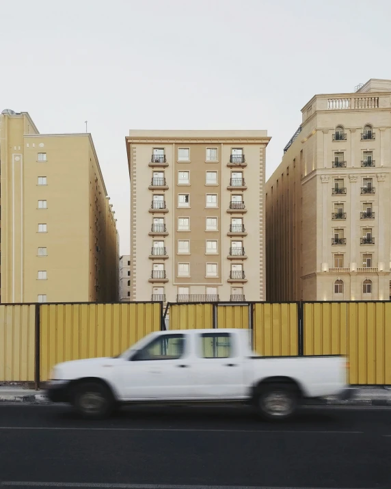 a car going past tall buildings near a fence