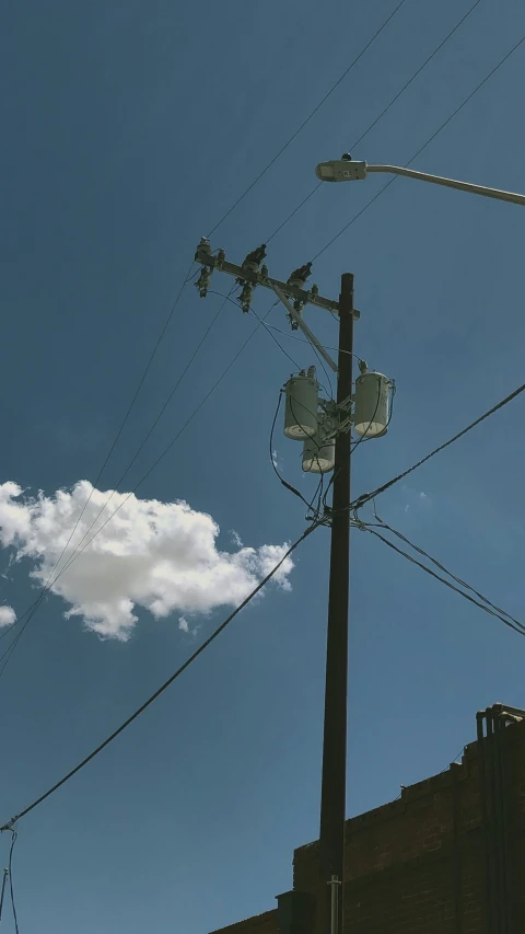 a white cloud in a blue sky and power lines