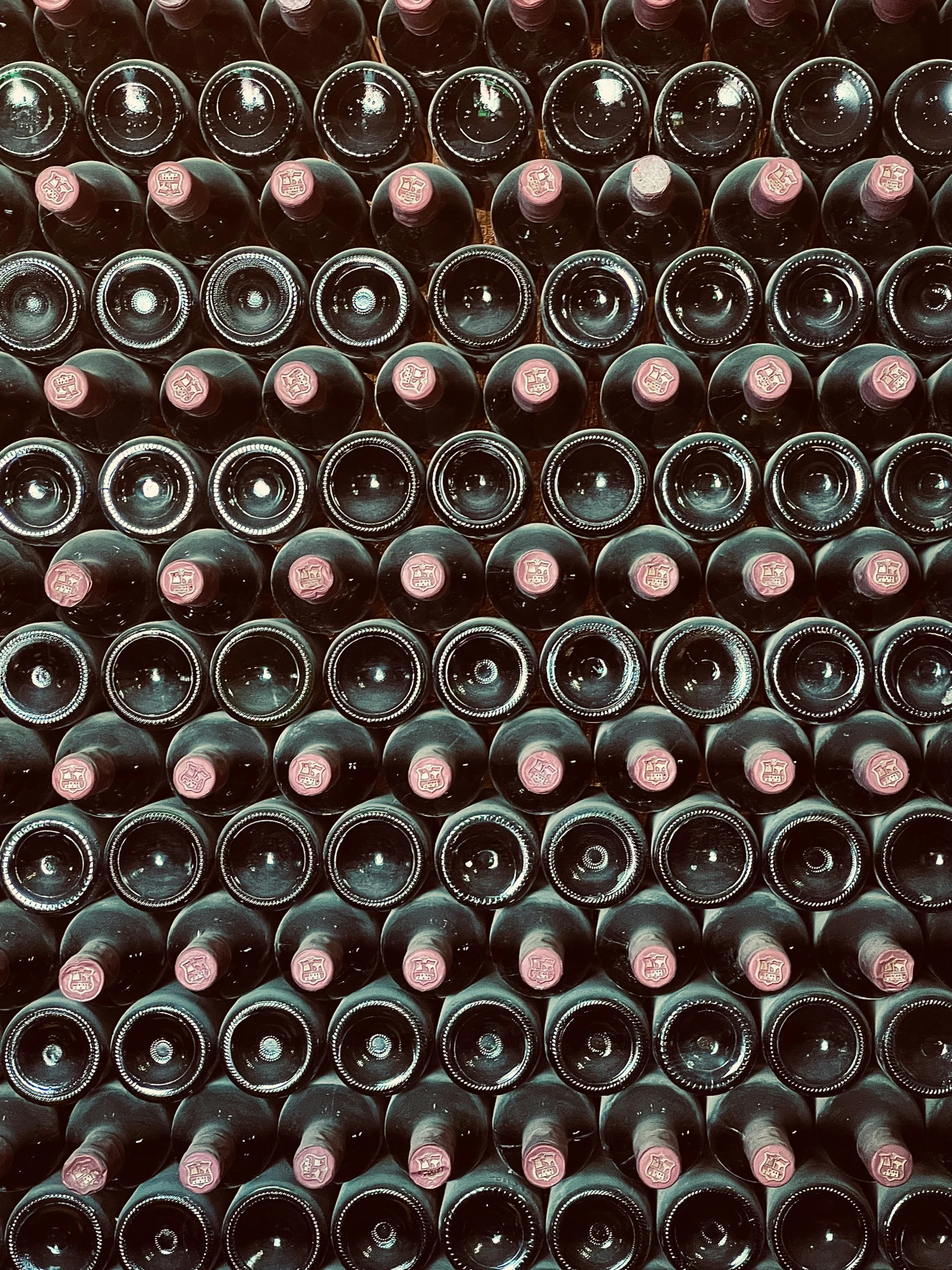 a wall full of black wine bottles next to each other