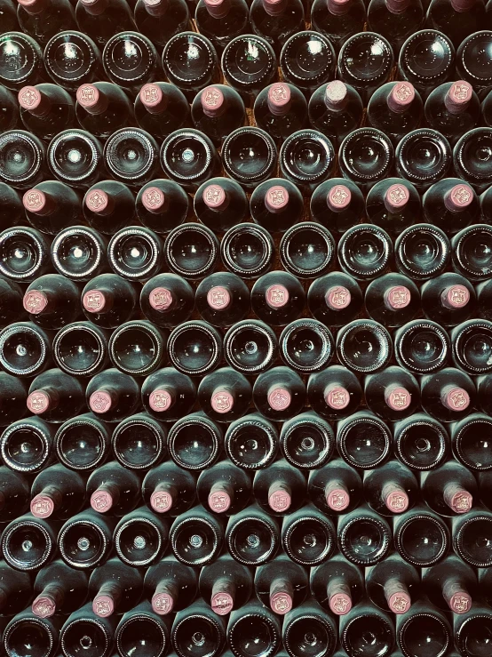 a wall full of black wine bottles next to each other