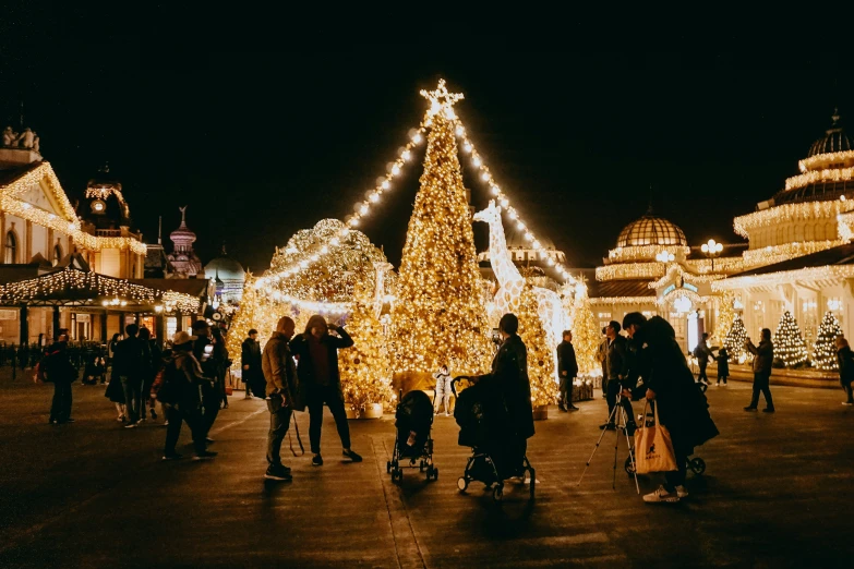 a bunch of people are walking by a lighted christmas tree