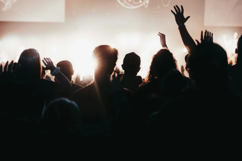 several people in a large concert crowd are waving their hands