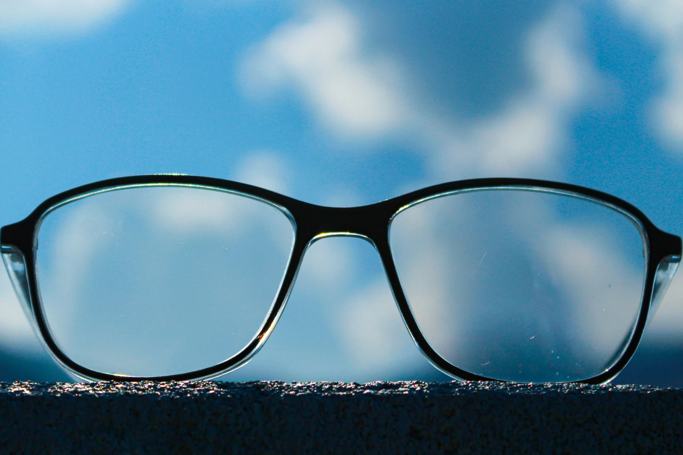 the glasses sit on the surface looking out at the blue sky