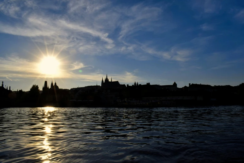 sun shines brightly above a large river and city skyline