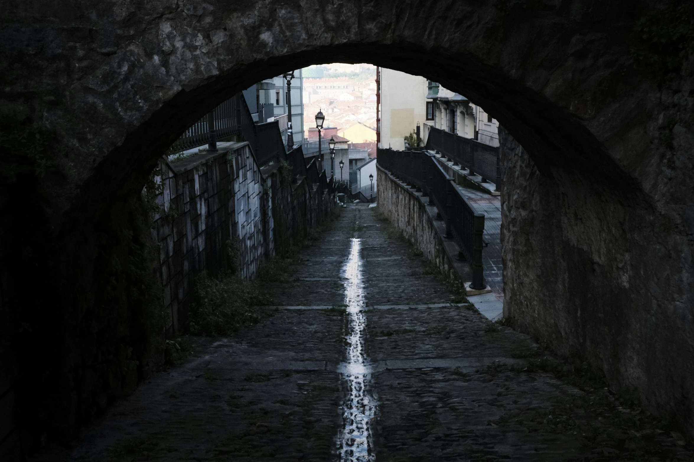 a tunnel in an old city has a clock tower and bell tower