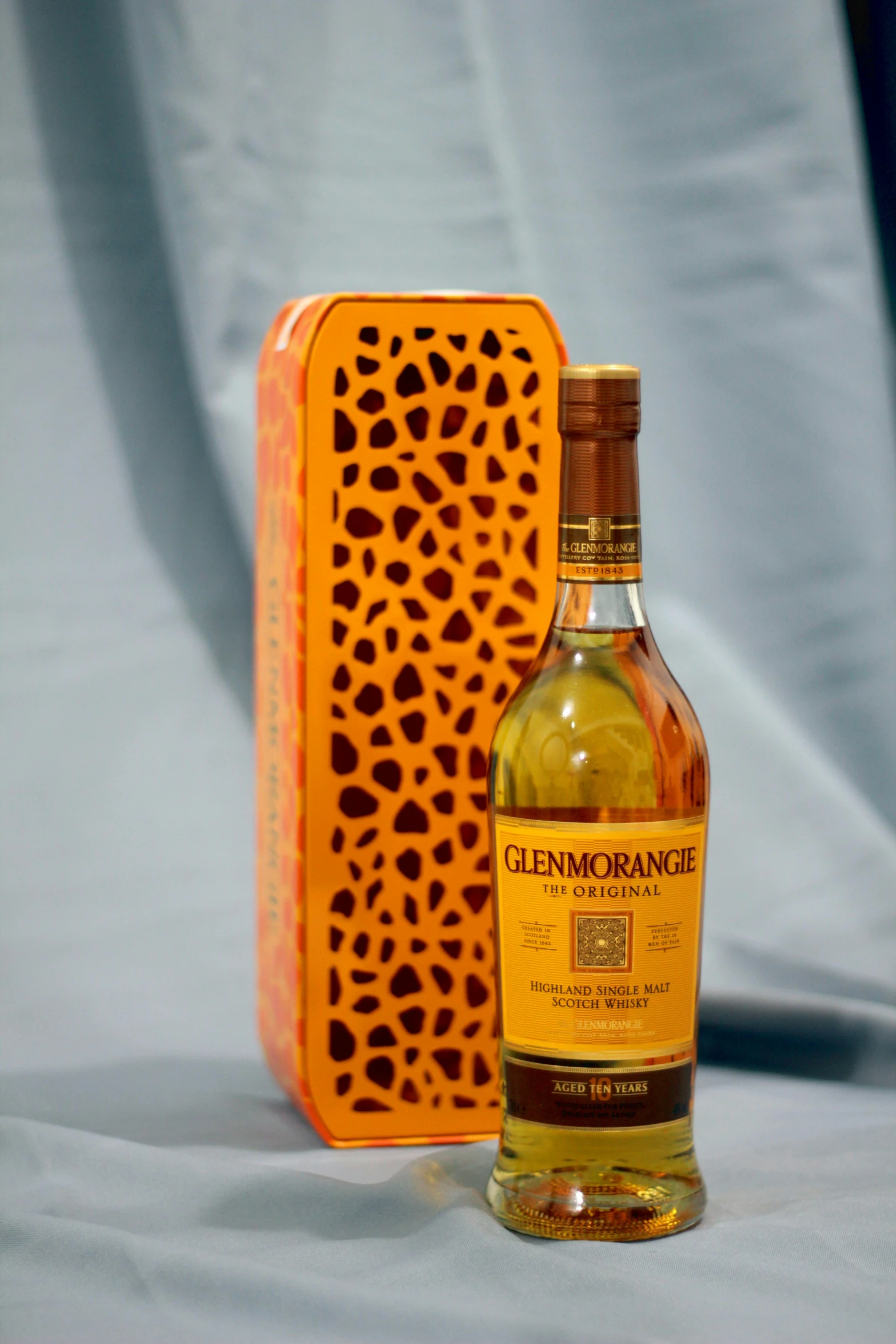 a bottle of whisky sitting next to a orange tin