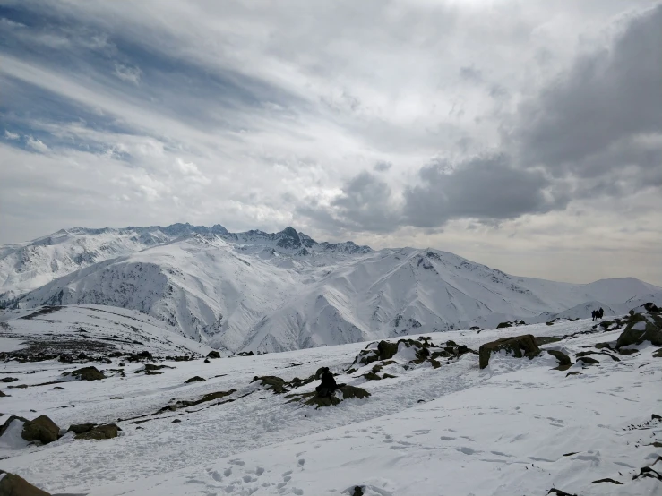 some snow mountains and rocks under the clouds