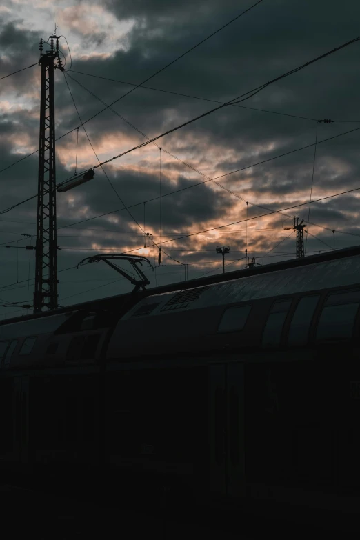 the top part of a train near many power lines and clouds