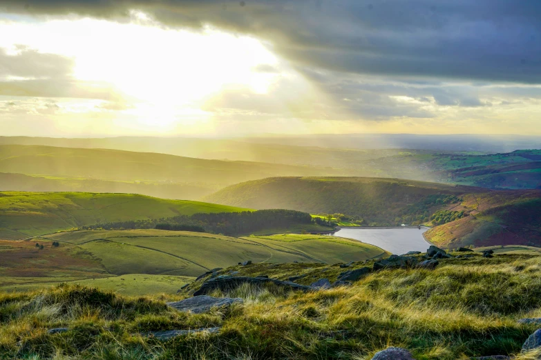 the sun shines brightly above a small lake in the distance