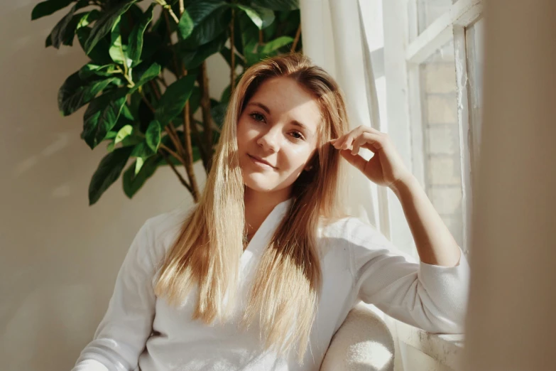 the woman sitting by a window poses for a picture