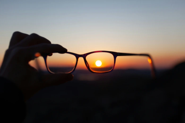 a person holding a pair of eye glasses to their face