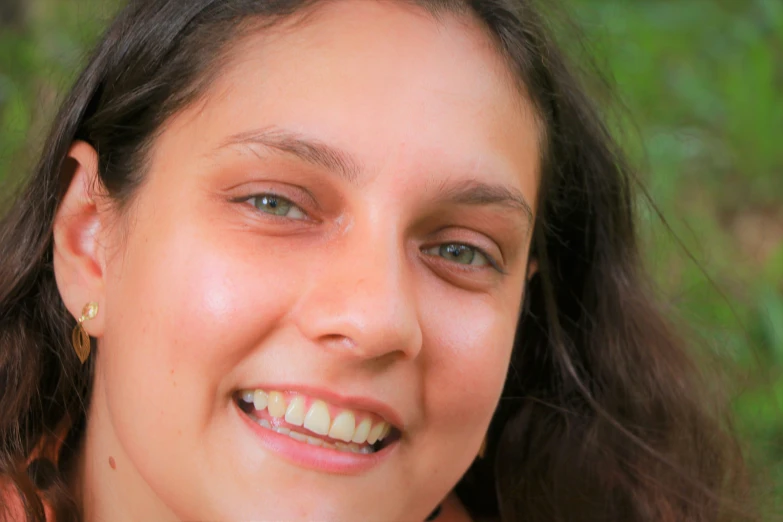 a woman smiles for the camera in front of a grassy area