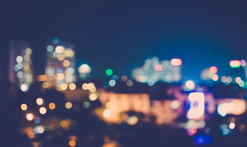 blurry pograph of city buildings at night, seen from a hill